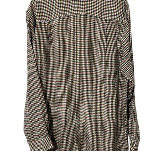 May include: A long-sleeved button-down shirt with a plaid pattern in shades of brown, green, red, and black.