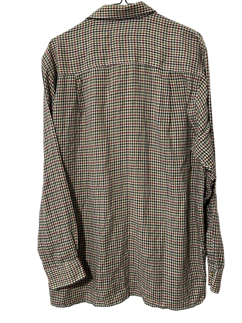 May include: A long-sleeved button-down shirt with a plaid pattern in shades of brown, green, red, and black.