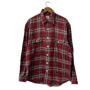May include: A red and white plaid long-sleeve button-down shirt with two chest pockets.