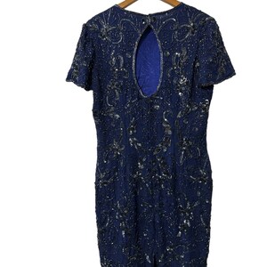 May include: A navy blue sequined dress with a keyhole back and short sleeves. The dress is fully covered in silver sequins in a floral pattern.