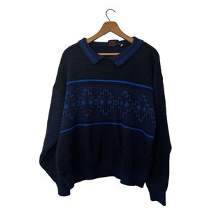May include: A dark blue sweater with a blue and white geometric pattern. The sweater has a collared neckline and long sleeves.