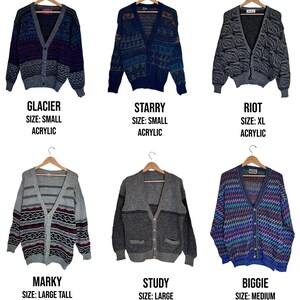 May include: Six vintage acrylic and wool cardigans in various colors and patterns are displayed on wooden hangers. Each cardigan has a unique design, with text labels indicating the style name, size, and material composition. The cardigans range in size from small to extra large.