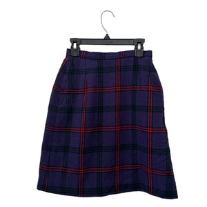 May include: A purple and red tartan skirt with a black hanger. The skirt has pockets on the sides.