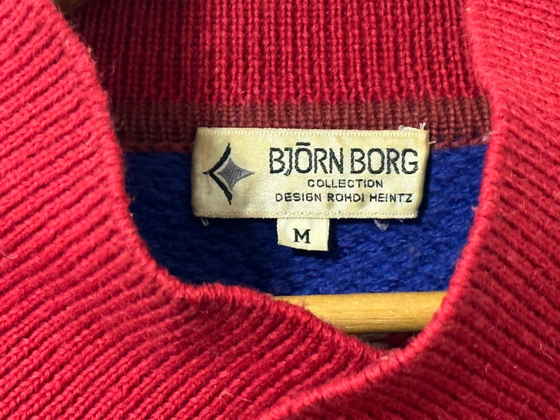 K&ouml;nnte beinhalten: Roter, blauer und brauner Strickpullover mit einem Bj&ouml;rn Borg-Etikett. Das Etikett lautet "Collection Design Rohdi Heintz" und "M".