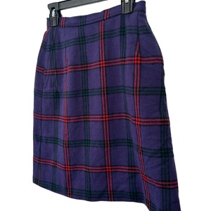 Op de afbeelding: Een paarse geruite rok met rode en groene strepen. De rok hangt aan een zwarte hanger.