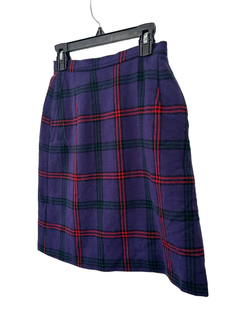 Op de afbeelding: Een paarse geruite rok met rode en groene strepen. De rok hangt aan een zwarte hanger.