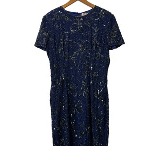 May include: A navy blue sequined dress with a short sleeve and a round neckline. The dress is covered in silver sequins in a floral pattern.