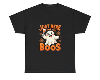 May include: Black t-shirt with a Halloween-themed graphic. The design features a cartoon ghost holding a wine glass, with the text "Just Here For The Boos" in orange and white. The ghost is smiling, and there are spiderwebs around the text.