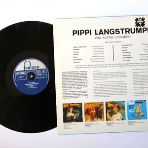 May include: A black vinyl record with a blue and white label next to a record sleeve. The sleeve features the title "PIPPI LANGSTRUMPF" and text in German. The record label reads "Fontana" and "33 ⅓".