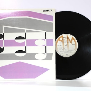 May include: A vinyl record album titled Waiata by Split Enz. The square cardboard sleeve features a geometric design in lavender, gray, and white with musical note graphics. Beside it lies the black vinyl record with a circular white center label.