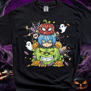 May include: A black short-sleeved t-shirt featuring a graphic print of three stacked pumpkins decorated as superheroes. The top pumpkin resembles Spider-Man, the middle has a Captain America mask, and the bottom is a green Hulk-like pumpkin.