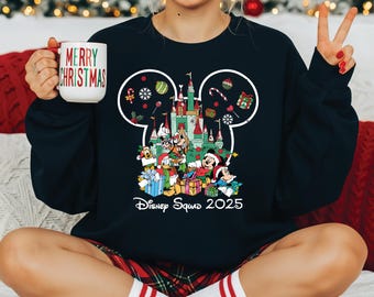 May include: A navy blue sweatshirt featuring a Mickey Mouse head outline with a castle and Disney characters. The sweatshirt has the text "Disney Squad 2025" and a "Merry Christmas" mug.