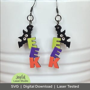 May include: Black bat-shaped earrings with the word "EEK" in lime green, purple, and orange. The earrings are laser-cut and feature a Halloween theme. The text "Joyful Laser Studio" is in the lower left corner.