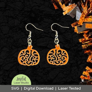 May include: A pair of orange pumpkin-shaped earrings with intricate cut-out designs. The earrings hang from silver-colored hooks. The image includes the text "Joyful Laser Studio" and "SVG | Digital Download | Laser Tested".
