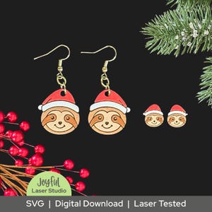 May include: Wooden sloth earrings and stud earrings, each wearing a red Santa hat with white trim. The earrings have gold-colored hooks. The image also includes text that reads "Joyful Laser Studio" and "SVG | Digital Download | Laser Tested."