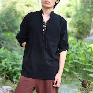 以下が含まれることがあります： 黒色の長袖シャツ。襟はスタンドカラーで、前面は編み上げのデザイン。袖は肘までまくられています。柔らかく通気性の良い生地で作られており、歴史的再現や普段着に最適です。