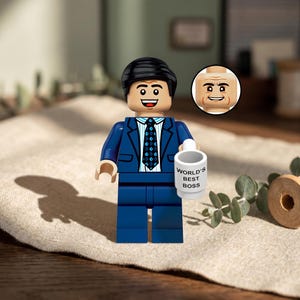 Könnte beinhalten: Eine Lego-Figur eines Mannes in einem blauen Anzug, der eine weiße Tasse mit der Aufschrift "WORLD'S BEST BOSS" hält. Die Figur hat schwarzes Haar und eine Krawatte mit blauem und weißem Muster. Ein alternativer Kopf wird in einem Kreis gezeigt.
