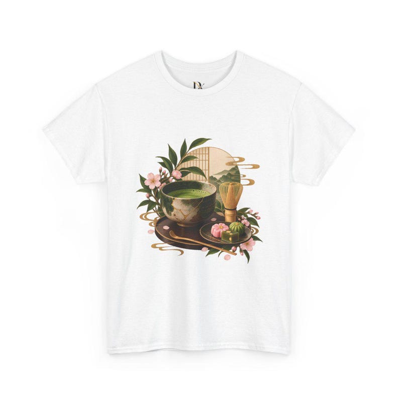 以下が含まれることがあります： 白いTシャツに、緑色の抹茶が入った茶碗、竹製の茶筅、そして暗い色の盆に乗った色とりどりの和菓子が描かれたグラフィックプリント。イラストにはピンクの桜の花、緑の葉、円形の背景要素が含まれています。