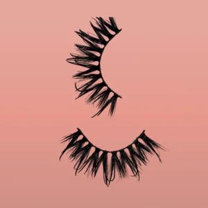 Peut inclure: Deux ensembles de faux cils noirs sur fond rose. Les cils sont épais et fournis, avec un design dramatique et épineux. L'image est un gros plan, mettant en valeur la texture et la forme des cils.