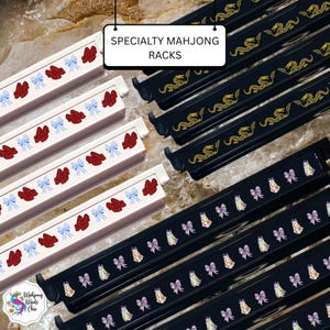 May include: A collection of specialty mahjong racks featuring various designs. The white racks display red shoes and blue gingham bows, while the black racks feature gold dragon motifs or patterns of purple bows and floral-patterned bunny figures.
