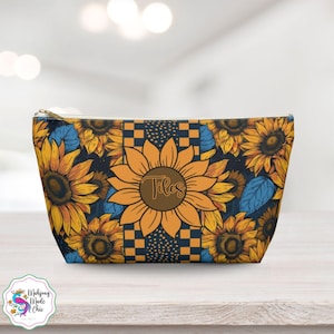 May include: A zippered pouch featuring a sunflower design with yellow petals and a brown center. The pouch has a navy blue background with additional sunflowers and blue leaves. The word "Tiles" is printed on the center sunflower.