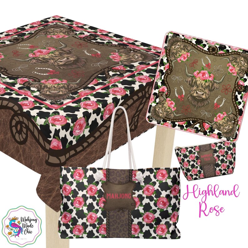 May include: A collection of Highland Rose themed items, including a tablecloth, tote bag, and cosmetic bag. The items feature a cowhide pattern with pink roses and a brown background with a Highland cow illustration. The tote bag has a brown leather-like patch with the name "Marjone".