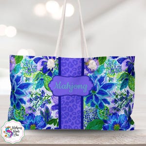 May include: A large tote bag with a floral pattern in shades of blue, purple, and green. The bag features a central purple panel with a leopard print and the word "Mahjong" in a decorative frame. White rope handles complete the design.