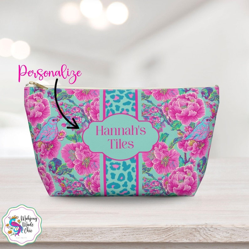 May include: A personalised cosmetic bag with a floral and bird pattern. The bag features a teal background with pink flowers and blue birds. The centre has a teal panel with the text "Hannah's Tiles".