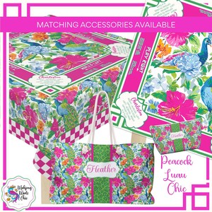 May include: A collection of Peacock Luau Chic accessories, including a tote bag, cosmetic bag, and tablecloth. The items feature a vibrant floral and peacock feather pattern with pink, green, blue, and orange hues. The tote bag has a green stripe with the name "Heather".