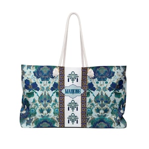 Könnte beinhalten: Große Tragetasche mit einem Blumenmuster in Blau- und Türkistönen. Die Tasche hat weiße Seilgriffe und ein zentrales Feld mit dem Wort "MAHJONG" in einem blauen Oval. Das Design beinhaltet einen griechischen Schlüsselrand.