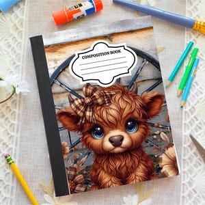 May include: Composition book featuring a brown Highland cow illustration with a plaid bow. The cover has a white label that reads "COMPOSITION BOOK". The notebook is on a white lace-trimmed surface with art supplies.