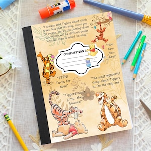 May include: Composition book featuring Tigger and Winnie the Pooh characters. The cover has quotes and illustrations of Tigger. The notebook is surrounded by art supplies and decorative elements.