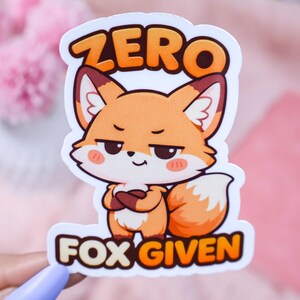 May include: A sticker featuring a cartoon fox with an orange and white color scheme. The fox has a smug expression and crossed arms. The text "ZERO FOX GIVEN" is printed above and below the fox in orange and white.