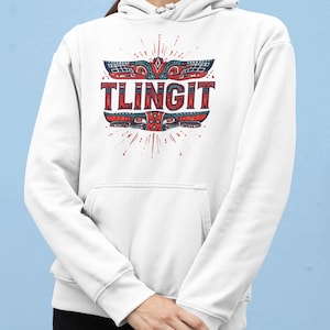 May include: White hoodie with a red, blue, and black graphic design that reads "TLINGIT." The design features a stylized totem-like image with radiating lines. The hoodie has a front pocket and a drawstring hood.