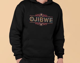 May include: Black hoodie with the word "OJIBWE" in colorful, patterned letters across the chest. The design features a decorative border with red, blue, and yellow accents. The hoodie has a front pocket and a hood.