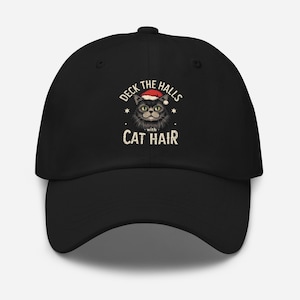 May include: Black baseball cap featuring a graphic of a cat wearing a Santa hat, with the text "Deck the Halls with Cat Hair." The design includes stars and a festive holiday theme.