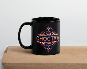 May include: A black ceramic mug with the word "CHOCTAW" in a colorful, geometric design. The mug is on a wooden surface.