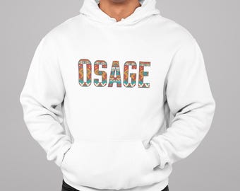 May include: White hooded sweatshirt with the word "OSAGE" in a colorful, patterned design across the chest. The design incorporates orange, teal, and brown geometric shapes. The sweatshirt has a front pocket and a drawstring hood.