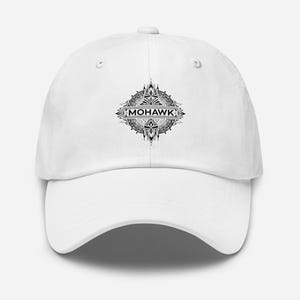 May include: A white baseball cap with a black and white decorative emblem and the word "MOHAWK". The cap has a curved peak and a six-panel design. The text is in a horizontal banner.