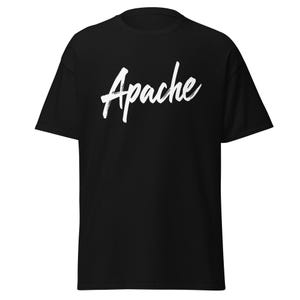 Puede incluir: Camiseta negra con la palabra "Apache" en blanco, con una fuente de estilo pincel en el pecho. La camiseta tiene mangas cortas y cuello redondo.