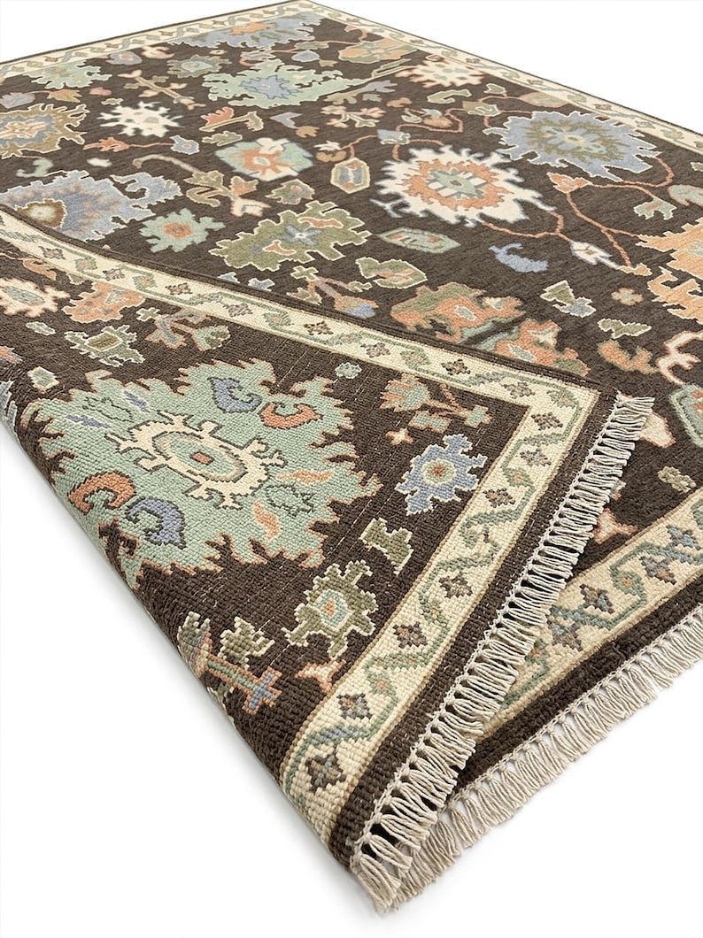 Peut inclure: Tapis marron fonc&eacute; avec un motif floral complexe dans des tons de bleu, vert et p&ecirc;che. Le tapis a une bordure cr&egrave;me et une frange. Le design est de style traditionnel, id&eacute;al pour un salon.