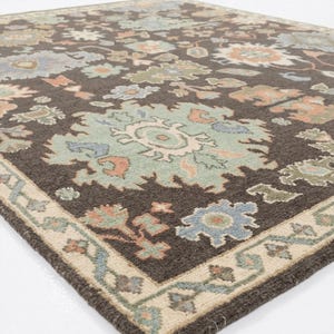 Peut inclure: Tapis marron &agrave; motifs floraux bleus, verts et p&ecirc;che. Le tapis a une bordure cr&egrave;me avec un motif floral r&eacute;p&eacute;t&eacute;. Fabriqu&eacute; en mat&eacute;riau tiss&eacute; doux, id&eacute;al pour un salon ou une chambre.