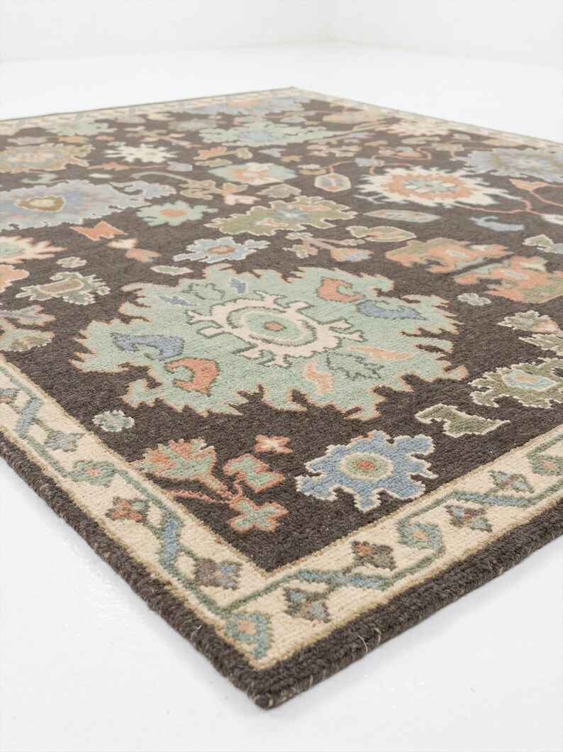 Peut inclure: Tapis marron &agrave; motifs floraux bleus, verts et p&ecirc;che. Le tapis a une bordure cr&egrave;me avec un motif floral r&eacute;p&eacute;t&eacute;. Fabriqu&eacute; en mat&eacute;riau tiss&eacute; doux, id&eacute;al pour un salon ou une chambre.