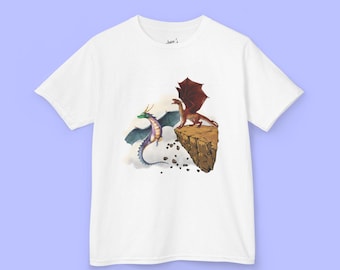 May include: White t-shirt featuring a colorful illustration of two dragons. One dragon is red with brown wings, perched on a brown rock formation. The other dragon is green and purple, with blue wings. The shirt has a crew neck.