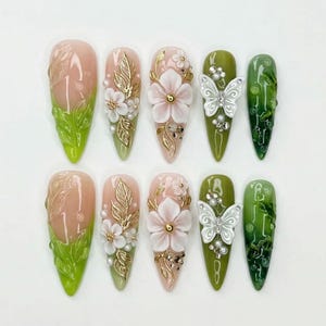 Unghie finte 3D a forma di farfalla, realizzate a mano, con decorazioni floreali e foresta verde, dettagli in foglia d'oro, perfette per un'atmosfera dolce e incantata.