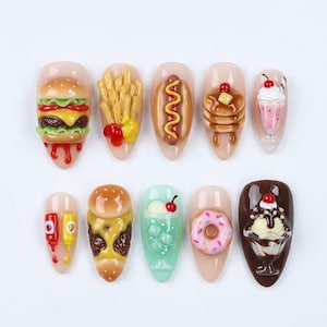 May include: A collection of ten nail art designs featuring miniature food items. Designs include a hamburger, french fries, hot dog, pancakes, milkshake, ketchup and mustard, cheeseburger, soda, donut, and ice cream sundae.