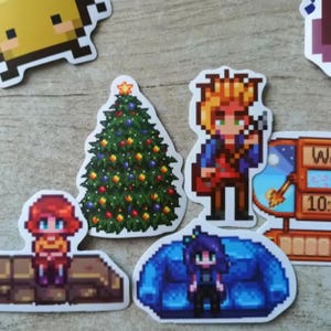 Peut inclure: Ensemble d'autocollants pixelis&eacute;s repr&eacute;sentant des personnages et des objets. Comprend un sapin de No&euml;l d&eacute;cor&eacute;, une personne jouant de la guitare et une personne assise sur un canap&eacute; bleu. Autres autocollants : une personne, une horloge et un carr&eacute; jaune.