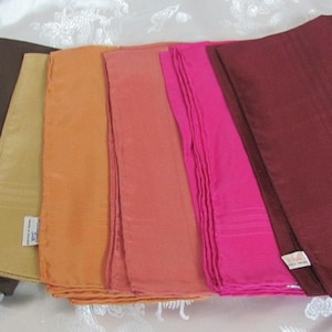 May include: Set of seven silk handkerchiefs in various colors, including brown, beige, orange, pink, and magenta. The handkerchiefs are folded and arranged in a row.