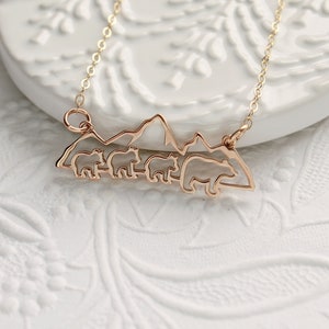 Op de afbeelding: Een gouden ketting met een hanger met een silhouet van een bergketen met vier beren die er voor lopen.