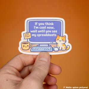 May include: A die-cut sticker featuring a computer monitor displaying the text If you think I'm cool now, wait until you see my spreadsheets. A yellow coffee mug with a face, a sticky note saying Don't forget!, and a cat are also shown.